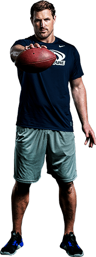 Jason Witten, former Dallas Tight End, wearing athletic clothes holding a football straight out in front of him