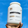 A hand holding up a large bottle of BodyLean25