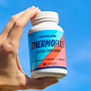 A hand holding up a bottle of ThermoPlus