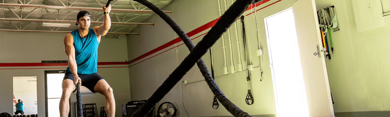 A man doing rope exercises at the gym.