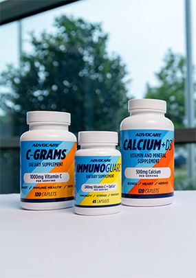 AdvoCare C-Grams, ImmunoGuard and Calcium + D3 bottles on a desk in front of a window.