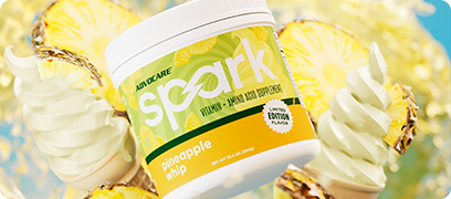 Spark Pineapple Whip canister surrounded by pineapple slices and ice cream cones.