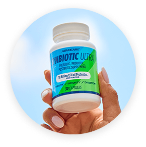 A hand holding a bottle of Synbiotic Ultra against a blue sky.
