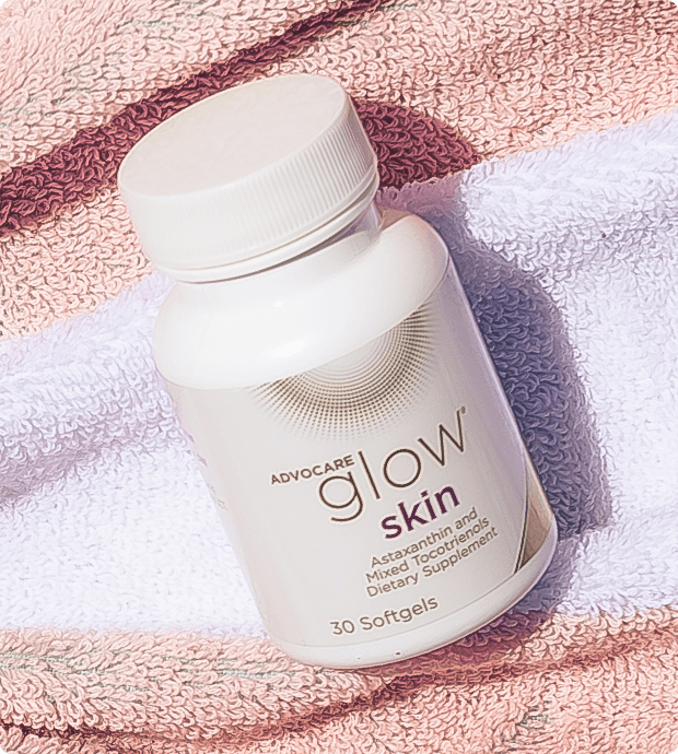 Bottle of Glow Skin on a beach towel.